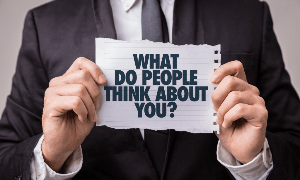 Man in pak houdt een bord vast met de tekst: "What do people think about you?"