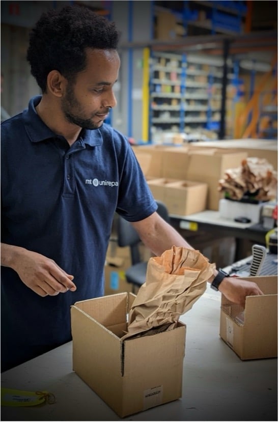 Medewerker van MT Unirepair verpakt onderdelen in kartonnen doos op logistieke werkplek