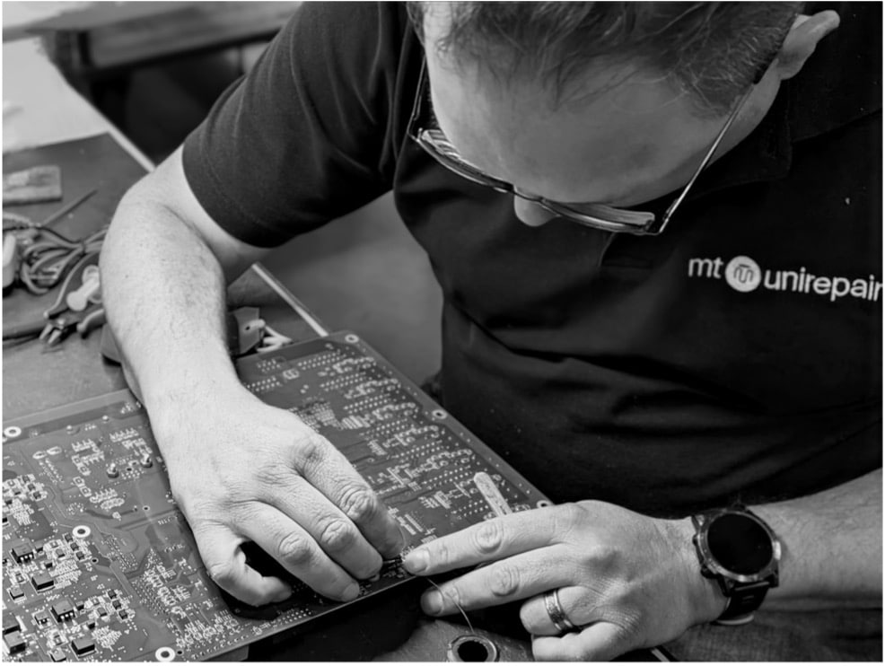 Expert inspecteert printplaat op werkbank bij MT Unirepair